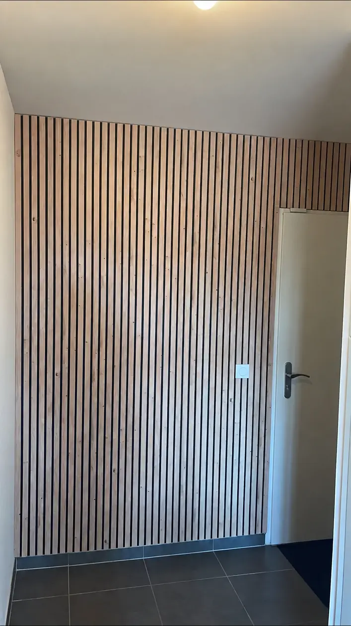 Même mur d'entrée entièrement habillé de tasseaux verticaux