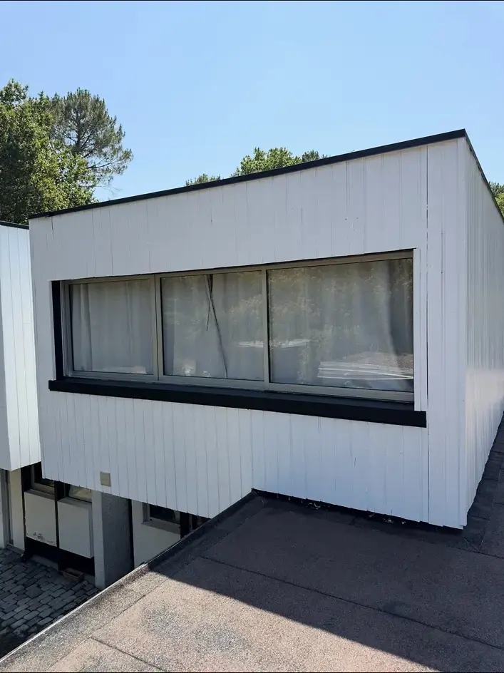 Bardage en bois rénové en blanc satiné avec détails noirs